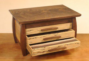 A wooden box with two drawers and a small drawer.