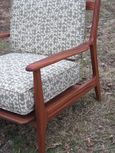 A chair with a wooden frame and grey patterned cushion.