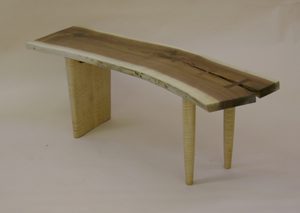 A wooden bench with legs and a slab of wood.