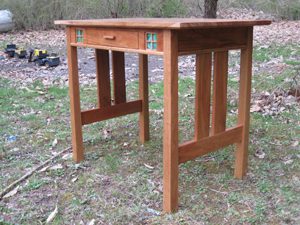 A wooden desk with a drawer and two legs.