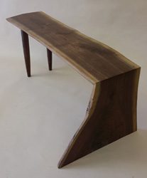 A wooden table with legs and a curved top.